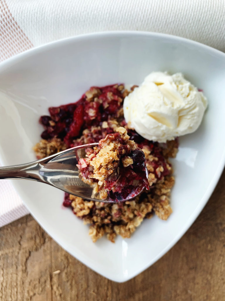 healthy mixed berry crisp with vanilla ice cream in a bowl 