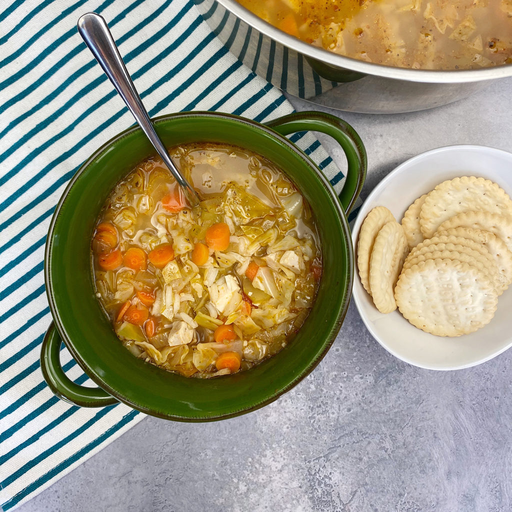 healthy chicken and cabbage soup with a bowl of crackers